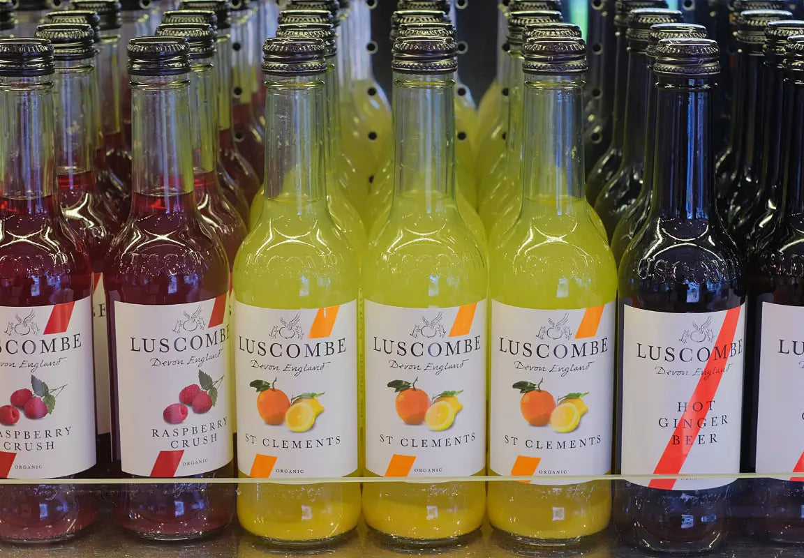 bottles of luscombe drinks, including raspberry crush, st clements, and hot ginger beer, displayed on a shelf
