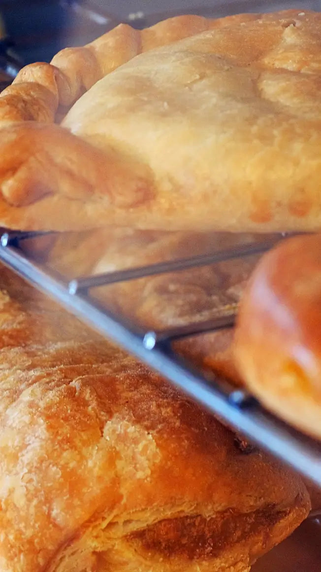 freshly baked pastries on a cooling rack, including a golden pie and a soft bun, with steam rising around them