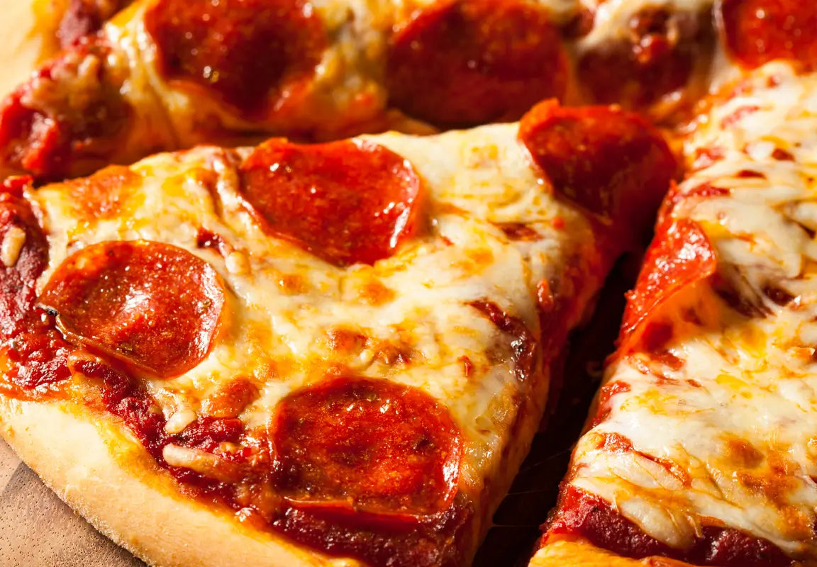 slices of pepperoni pizza with melted cheese and tomato sauce on a wooden board