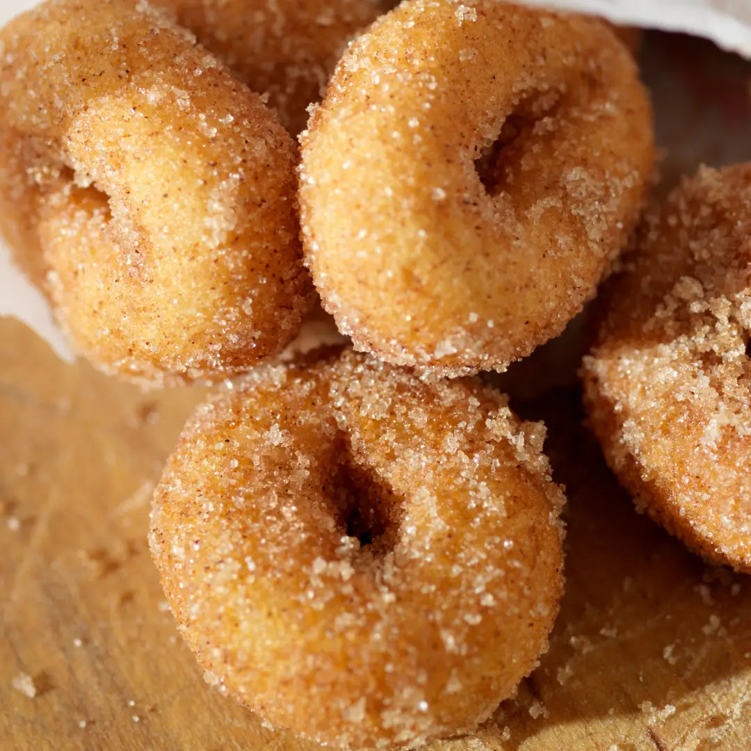 five cinnamon sugar-coated doughnuts on a wooden surface