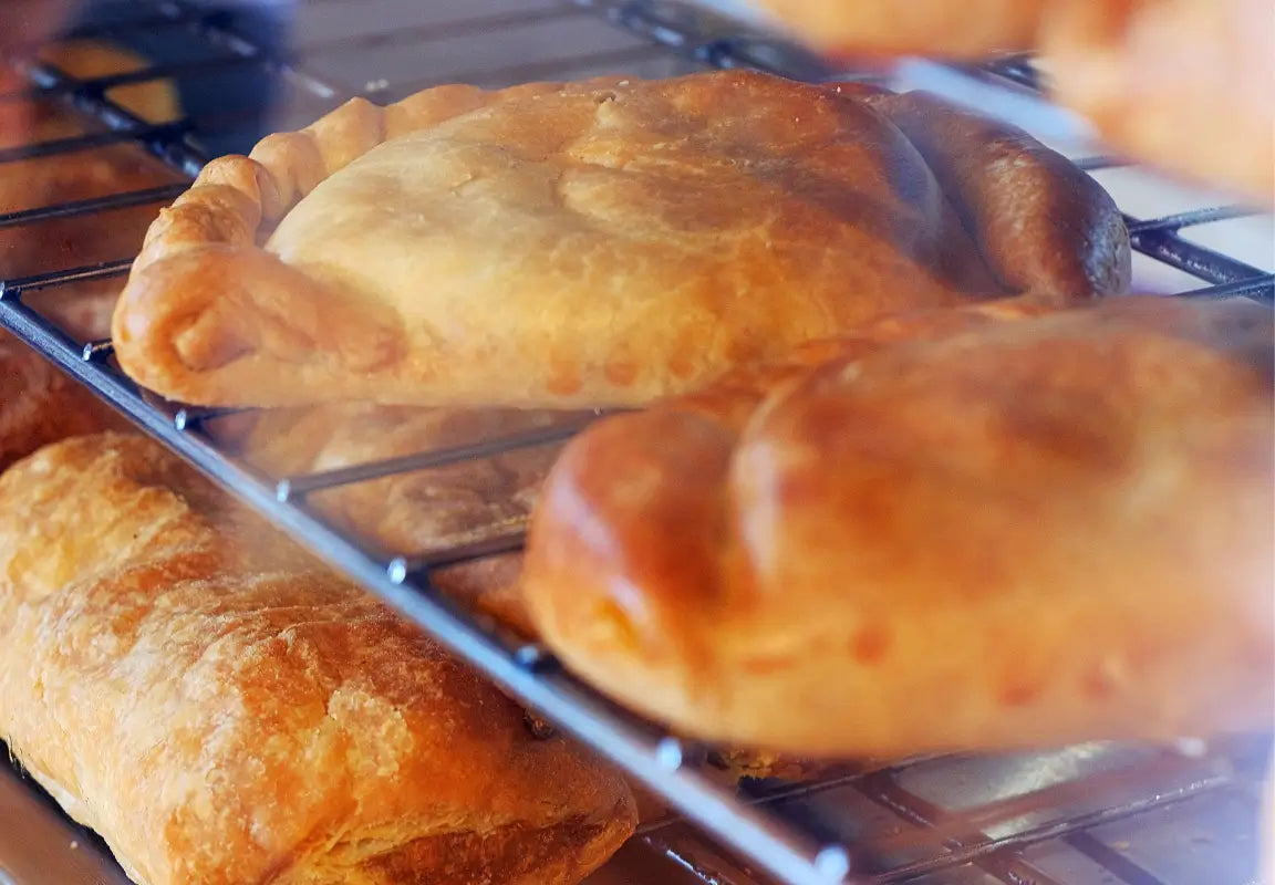 freshly baked pastries on a cooling rack, golden brown and flaky, with steam rising from them