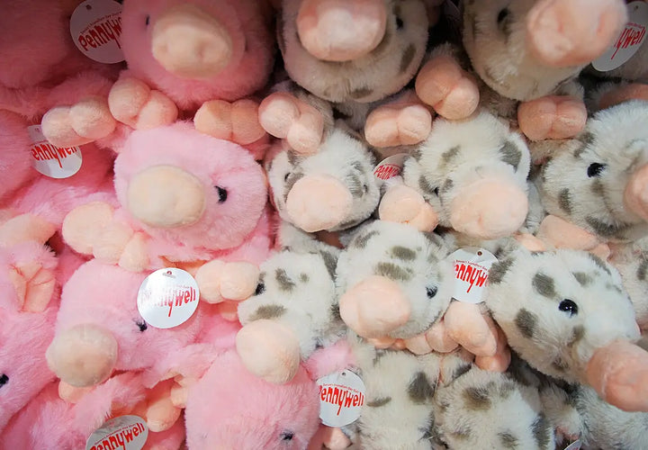 a collection of pink and grey plush pig toys with small tags, stacked closely together